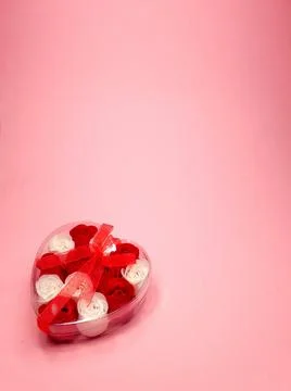 Transparent gift box with a ribbon in the shape of a heart with small flowers Stock Photos