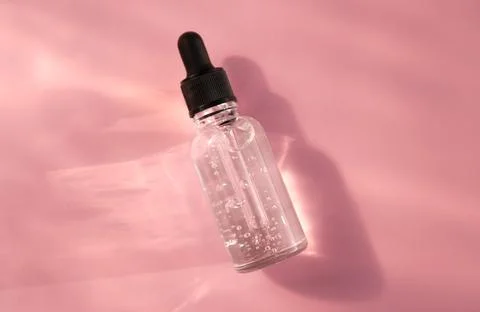 Transparent glass dropper bottle with air bubbles on pink background in the Stock Photos