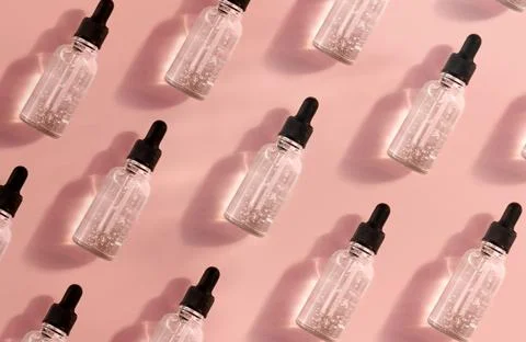 Transparent glass dropper bottle with air bubbles pattern on pink background in Stock Photos