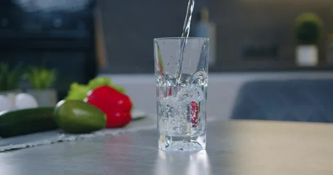 Transparent glass standing on the table top near vegetables and is filled with Stock Footage 148738253
