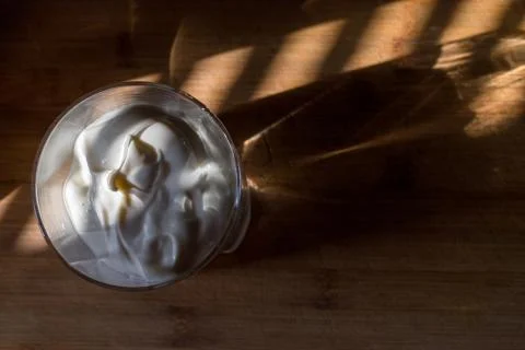 A transparent glass with thick white cream warmly illuminated by a beautiful Stock Photos