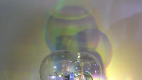 Transparent globes spin and reflect shifting colors in soft glowing light. Stock Footage 302411247