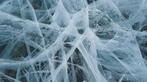 Transparent ice of lake Baikal with a pattern of cracks Stock Photos