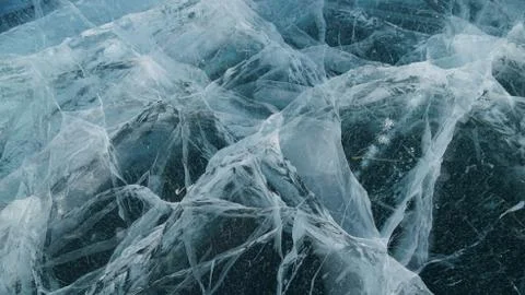 Transparent ice of lake Baikal with a pattern of cracks Stock Photos