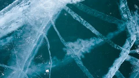 Transparent ice of lake Baikal with a pattern of cracks Stock Photos