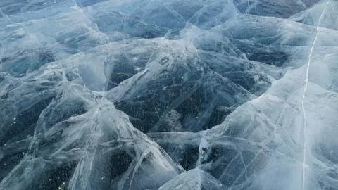 Transparent ice of lake Baikal with a pattern of cracks Stock Photos