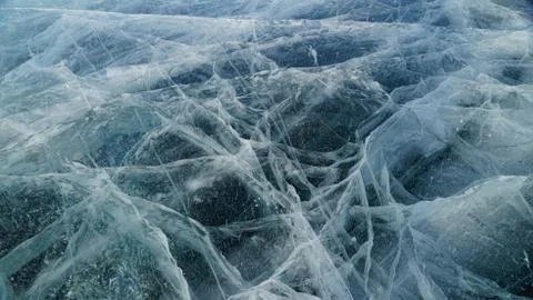 Transparent ice of lake Baikal with a pattern of cracks Stock Photos