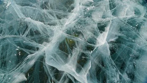 Transparent ice of lake Baikal with a pattern of cracks Stock Photos