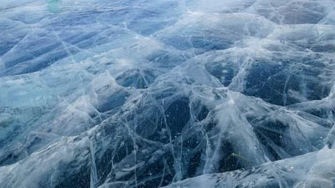 Transparent ice of lake Baikal with a pattern of cracks Stock Photos