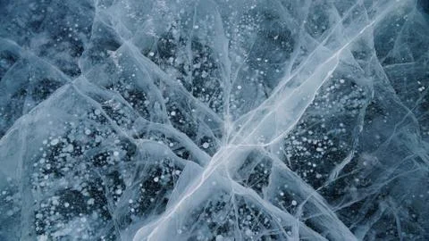 Transparent ice of lake Baikal with a pattern of cracks Stock Photos