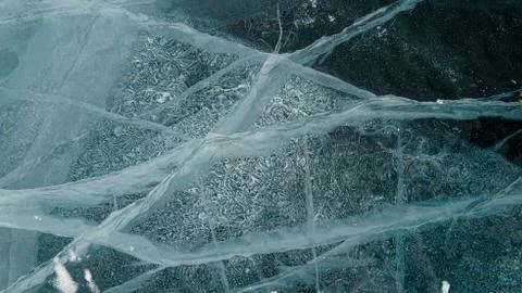 Transparent ice of lake Baikal with a pattern of cracks Stock Photos