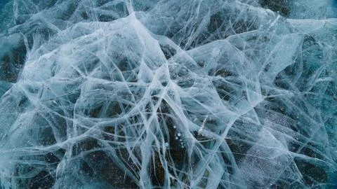 Transparent ice of lake Baikal with a pattern of cracks Stock Photos