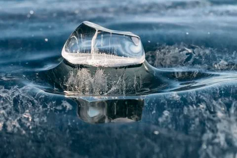 Transparent icicle with a beautiful pattern on the ice of lake B Stock Photos