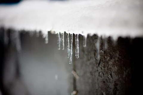 Transparent icicles hang from the roof. Winter Stock Photos
