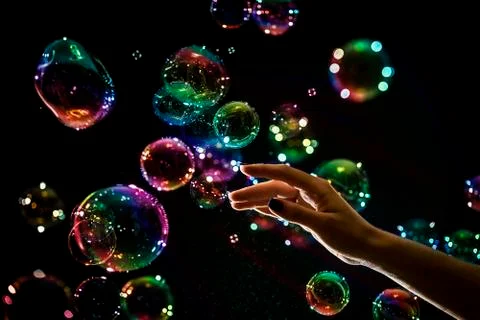 The transparent, iridescent soap bubbles isolated on black. Photos