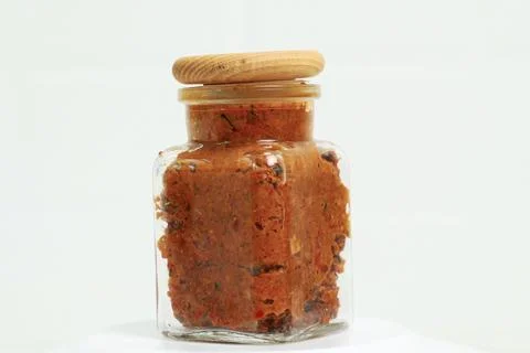 Transparent jar with adjika on a white table. Stock Photos