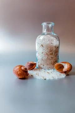 A transparent jar of sea white salt stands against a metal background. Stock Photos