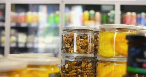 Transparent jars filled with walnuts and dried mango slices are stacked on a Stock Footage 309046148