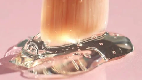 Transparent liquid beauty texture with bubbles on a pink background Stock Footage 234875266