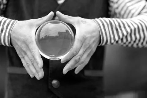 Transparent magic ball with reflection in the hands of a clown Stock Photos