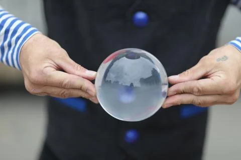 Transparent magic ball with reflection in the hands of a clown Stock Photos