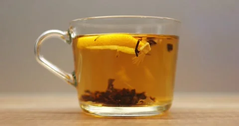 Transparent mug filled with herbal tea and fresh lemon slice on wooden table Video stock 290889071