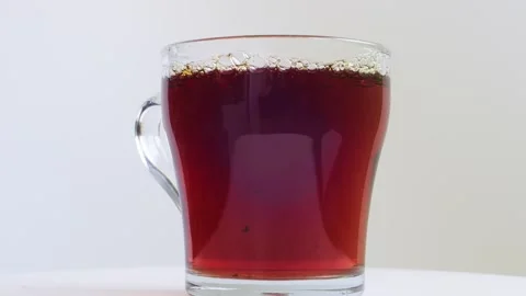 Transparent mug of strong brewed tea spins in a circle on a white backgroun.. Vidéo 288371790