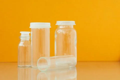 Transparent phials on yellow background. Small empty bottles Stock Photos