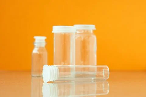 Transparent phials on yellow background. Small empty bottles Stock Photos