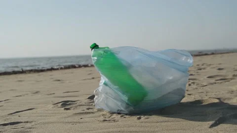 Transparent plastic bag full of garbage on a sandy beach, close-up. Stock Footage 192953232
