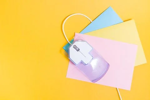 Transparent plastic computer mouse and paper colored envelopes on a yellow ba Stock Photos