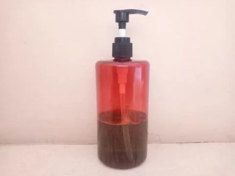 Transparent Plastic Pump Bottle Filled with Dark Liquid with Plain Background Stock Photos
