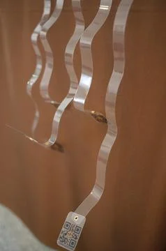 Transparent plastic strips with QR code hanging against a brown background Stock Photos