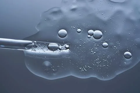 Transparent serum with bubbles and dropper dropper on a blue background. Stock Photos