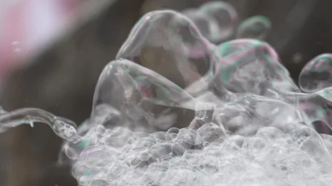 Transparent soap bubbles stack near a foam outlet as thin films catch light.. Stock Footage 324896346