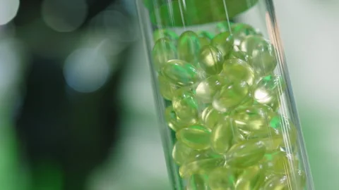 Transparent softgel capsules in lab container with green lighting Stock Footage 310207326