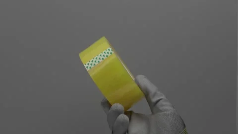 Transparent tape in hand on a gray background. Vidéo 265596799