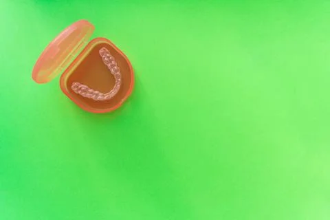 Transparent tooth aligner in red case on green background Stock Photos