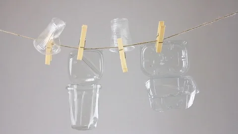 Transparent trash hangs on clothesline, plastic disposable tableware reuse Stockbeeldmateriaal 112366724