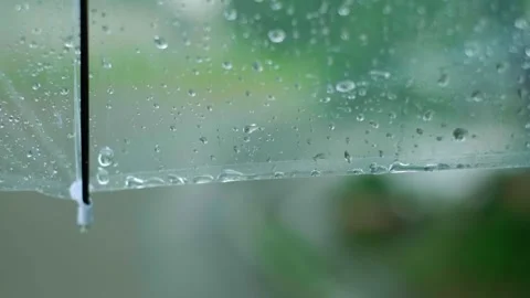 A transparent umbrella with raindrops sliding down it during a rainy day, promot Stock Footage 277643026