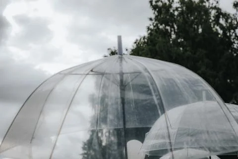 Transparent umbrellas with a dome shape positioned outdoors against a cloud.. 写真素材