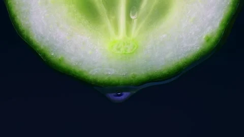 Transparent water drop falling down from bright green cucumber slice Stock Footage 268873921