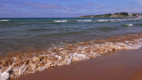 Transparent waves roll on a sandy beach in a sunny day Stock Footage 93373797