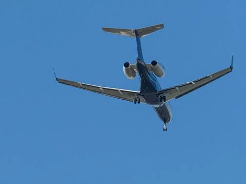 A transport plane flies in the blue cloudless sky Stock Photos
