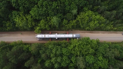 Transporting a large pipe / reactor on a road through a forest on a summer day. Stock Footage 124244941