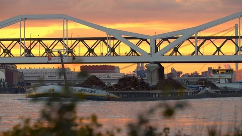 Transporting Trash on a Boat passing under Modern Bridge in Mannheim at Sunset Видео 120554084