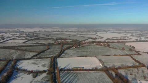Transverse flight over a patchwork of snowy fields in winter sunshine, blue sky Video stock 226392718
