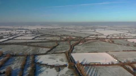 Transverse flight over a patchwork of snowy fields in winter sunshine, blue sky Video stock 226393807