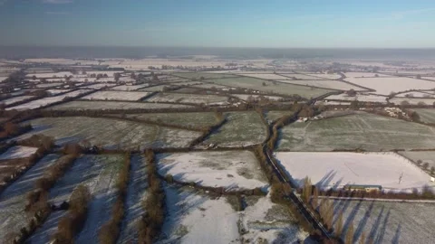 Transverse flight over a patchwork of snowy fields in winter sunshine, blue sky Video stock 226396938