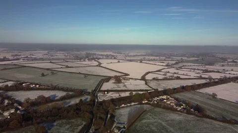 Transverse flight over a patchwork of snowy fields in winter sunshine, blue sky Video stock 226539199